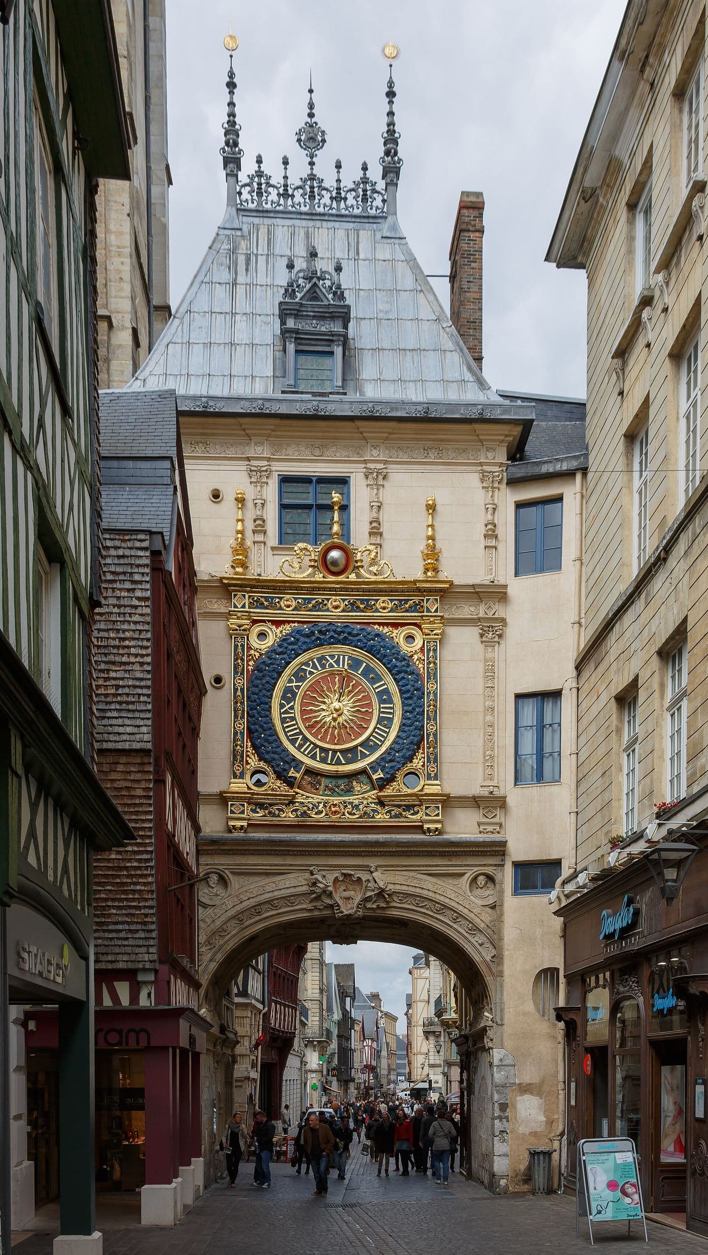 La tour du Gros-Horloge et son cadran doré, au-dessus d'une rue du centre historique de Rouen